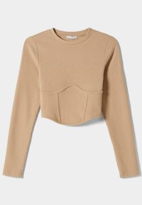 Haut court beige à manches longues côtelées avec encolure ronde et détail de couture incurvée sous la poitrine, posé à plat sur fond blanc.
