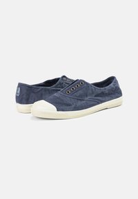 Tengerészkék vászon slip-on cipők fehér gumitalppal és orrésszel, fém fűzőlyukakkal és strukturált felülettel.