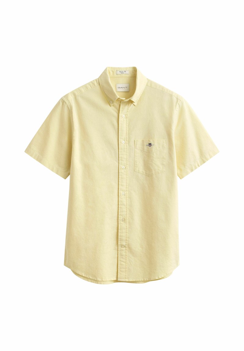 Camisa amarilla clara de manga corta con botones, bolsillo en el pecho y pequeño logo bordado en el bolsillo, con cuello abotonado.