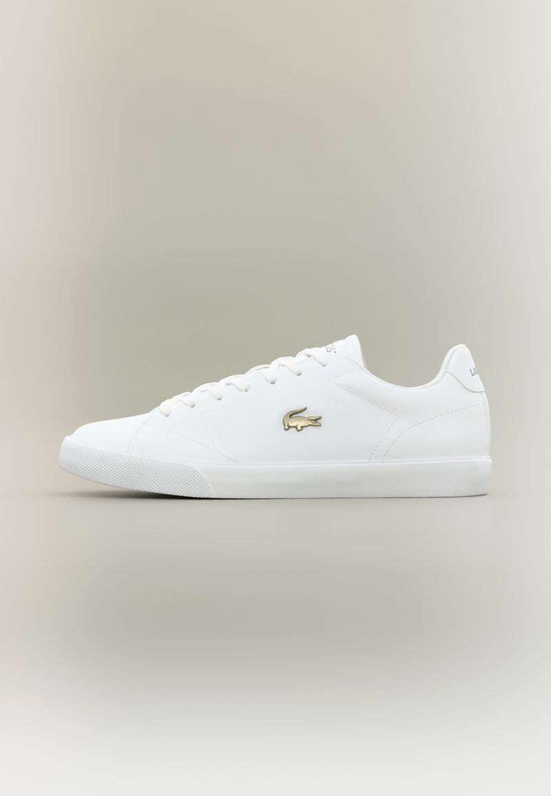 Hvite lær sneakers med gull logo, flate lisser, teksturert hvit såle, rund tå og minimalistisk design.