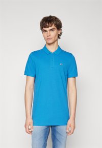 Polo blu realizzato in cotone, con colletto, maniche corte e un piccolo logo del marchio sulla parte sinistra del petto.