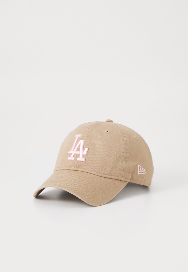 Casquette de baseball beige avec logo "LA" brodé en rose à l'avant et logo New Era rose sur le côté, posée sur un fond blanc.