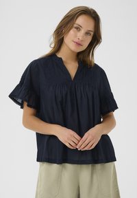 Blusa di cotone blu navy con colletto alla cinese, maniche corte a campana con dettagli in pizzo e arricciature sul busto.