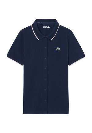 Donkerblauw poloshirt met korte mouwen, knoopsluiting en witte biezen aan kraag en mouwen, met een groen krokodillenlogo op de borst.