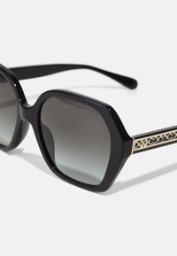 Ochelari de soare negri cu ramă octagonală, lentile gri degradé și accente aurii cu un model pe laterale. Material plastic neted.