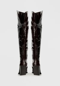 Bordowe, błyszczące kozaki za kolano z kwadratowym obcasem, zwężaną cholewką i pionowymi przeszyciami. Zamek błyskawiczny z boku dla łatwości noszenia.