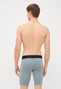 Herre badetights i lyseblå med sort elastisk talje og lommer. Glat tekstur, knælangt design og strækbart materiale.