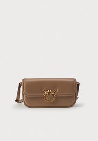 Bolso cruzado de cuero marrón con cierre de solapa, que presenta un motivo de ave en tono dorado y un detalle de hardware circular. Textura suave, correa ajustable.
