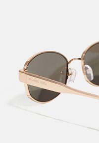 Ochelari de soare rotunzi cu lentile întunecate; cadru din metal de culoare aurie; gravat "MICHAEL KORS" pe braț; pernuțe nazale clare pentru confort.
