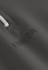 Zwarte stof met een gladde textuur, voorzien van een reliëf "FRIEDA" logo en een zilverkleurige rits, met een minimalistisch ontwerp.