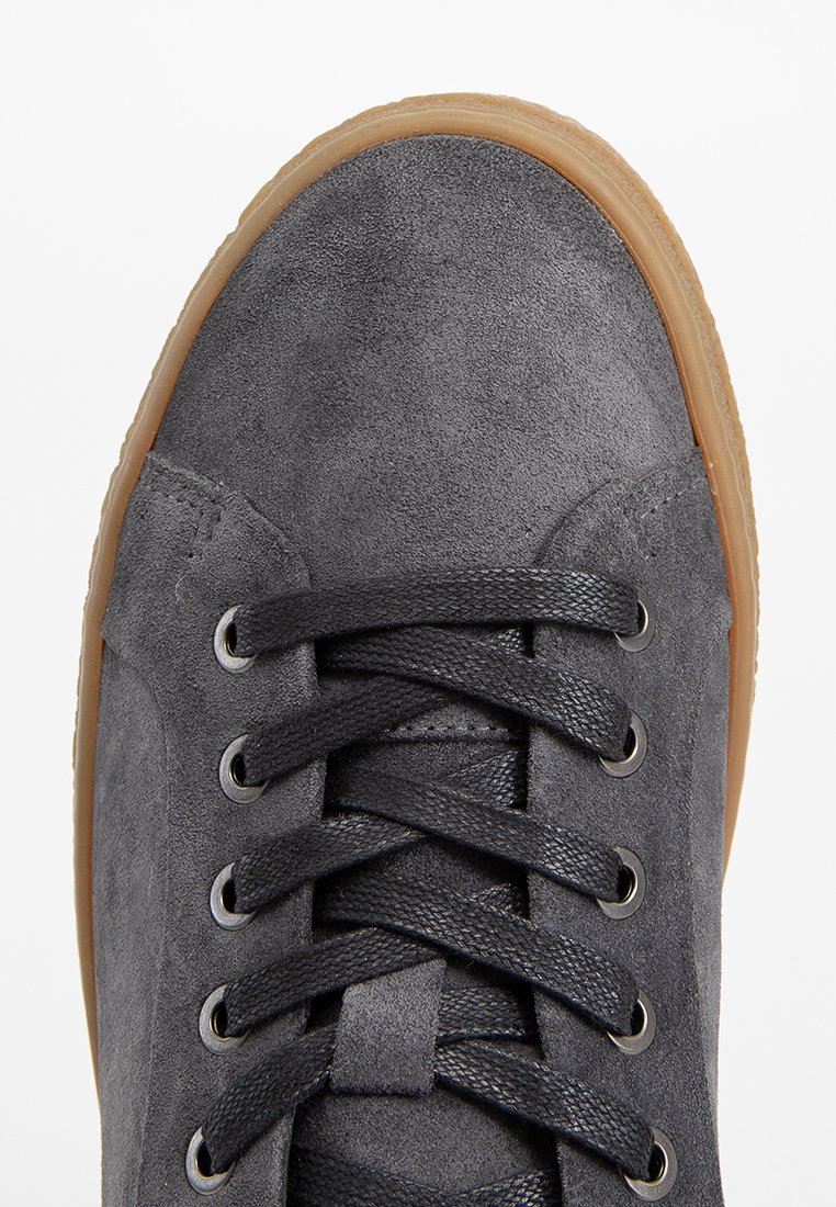 Szare zamszowe sneakersy z okrugłym noskiem, płaskimi sznurowadłami i metalowymi oczkami. Podeszwa z gumy z teksturowanym detalem na krawędziach.