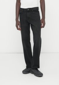 Fekete egyenes szárú farmernadrág klasszikus szabással, farmer anyagból készült, elülső és hátsó zsebekkel, gombos záródással és finom varrási részletekkel.