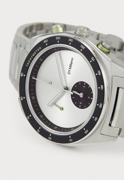 Hõbedane käekell ümmarguse näo, musta taksimetra äärisega, minimalistliku disainiga, roheliste aktsentidega ning hõbeda ja mustade kelladeatega.