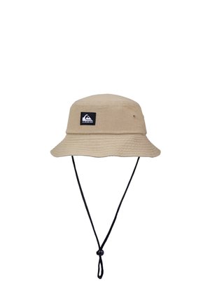 Beige bucket hat made of fabric with a black logo patch, wide brim, and adjustable black chin strap for secure fit.