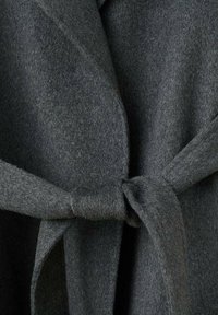 Cappotto avvolgente in tessuto di feltro grigio scuro con una texture morbida. Presenta una cintura annodata e un design con colletto sovrapposto. Nessuna ferramenta o motivo visibile.