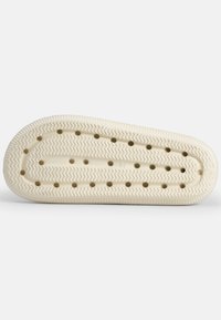 Suola in gomma di colore bianco sporco con un motivo a zigzag. Presenta fori di drenaggio uniformemente distanziati lungo la lunghezza per migliorare la trazione.
