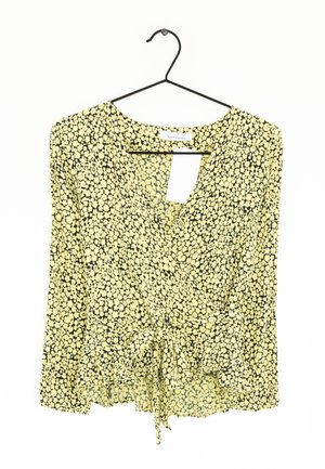 Geel bloemenblouse met een wikkelontwerp, V-hals en een geplooide peplumzoom. Heeft een zwart bloemenpatroon op lichtgewicht stof.