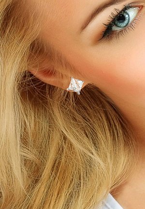 Boucles d'oreilles en forme de diamant clair avec des montures en argent, présentant une surface texturée et une légère touche de détail rose.