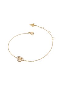 Bracciale in oro con ciondolo a forma di cuore decorato con cristalli chiari e inciso con "Guess." Include un gancio a moschettone e lunghezza regolabile.