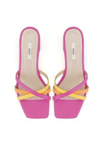Pink heeled sandals with square toes, featuring bold yellow and orange straps that crisscross over a smooth, light-colored insole.