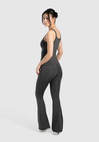 Canotta grigia aderente e pantaloni a palazzo realizzati in tessuto elasticizzato, con una texture liscia e un design minimalista senza pattern.