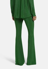 Groene glitters stofset bestaande uit een losse top en flared broek, met een gladde textuur en glanzende afwerking, die een getailleerde silhouet benadrukt.