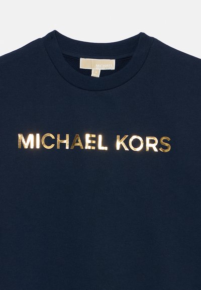 Temno moder bombažna srajca z okrogelim izrezom in zlatim kovinskim logotipom "MICHAEL KORS" čez prsi. Gladka tekstura.