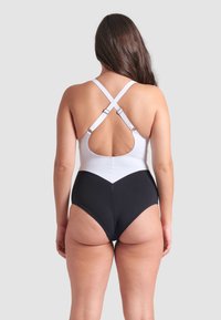Zwart-witte eenpiece zwempak met een racerback ontwerp, voorzien van verstelbare bandjes en een chevronpatroon bij de taille.