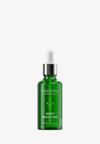 Groene glazen pipetfles met een zilveren dop, gelabeld "MÁDARA DEEP MOISTURE VITAMIN OIL," met een minimalistisch ontwerp en een logo voor biologische certificering.