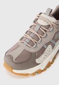 Skechers tenisice s mrežastim gornjim dijelom u taupe nijansi i svijetloplavi akcentima, s gumenim potplatom i udobnim dizajnom.