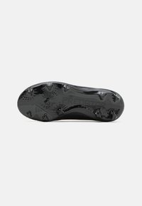 Suela de botas de fútbol negras con tacos moldeados para tracción, que presenta la marca "PREDATOR" y una superficie lisa y texturizada.