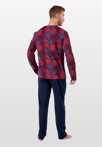 Langärmliges Schlafanzug-Oberteil mit einem kastanienbraunen Grundton, das mit einem floralem Muster in Rot und Blau verziert ist; kombiniert mit marineblauen, geraden Hosen.