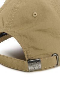 Casquette kaki en tissu texturé à rayures verticales. Elle présente un régulateur en métal avec des accents gravés et un bouton cousu sur la calotte.