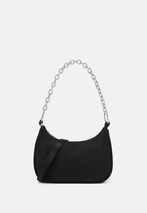 Schwarze handtasche in halbmondform mit silberner kettenhenkel und zusätzlichem schwarzem schulterriemen auf einfarbigem hintergrund.