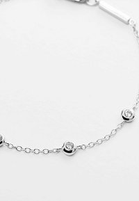 Bracciale in argento con tre accenti in cristallo trasparente rotondi, equidistanti lungo la lunghezza. Finitura liscia e lucidata.