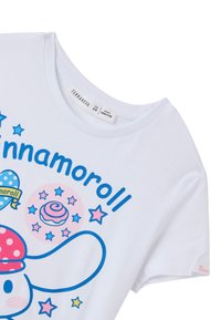 T-shirt bianco a maniche corte con grafiche in stile cartone animato blu e rosa, inclusi un personaggio con un cappello a pois e motivi a stella.