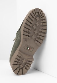 Suola in suede verde con una suola in gomma texturizzata. Presenta una scanalatura a forma di stella e un'etichetta di branding. Taglia 37 indicata.