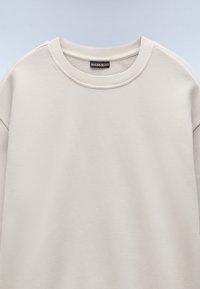 Licht beige sweatshirt met een ronde hals, ribboord aan de mouwen en onderkant, gemaakt van zachte stof, met een effen textuur zonder patronen.
