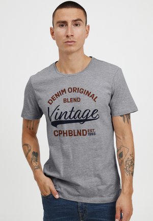 Grå bomull t-skjorte med grafisk trykk i mørk blå og brun, med teksten "DENIM ORIGINAL BLEND Vintage CPHBLND EST. 1993." Korte ermer.