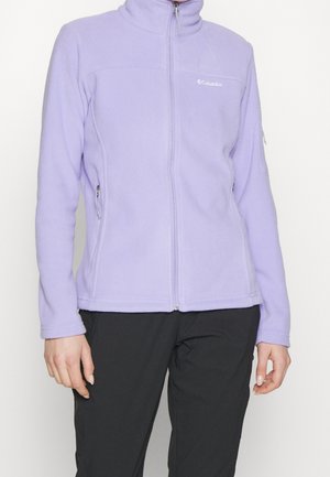 Osoba ubrana w jasnofioletową polarową kurtkę Columbia z zamkiem błyskawicznym z przodu i zapinanymi na zamek bocznymi kieszeniami, w połączeniu z czarnymi spodniami.