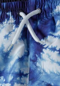 Plave i bijele kupaće gaće s uzorkom tie-dye, elastičnim pojasom i bijelim vezicom. Ima detalje u šivanju i glatku, laganu tkaninu.