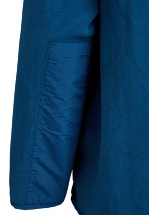 Blue fleece jacket detail showing textured fabric with a smooth woven pocket. Features a vibrant, uniform color and soft, warm texture.