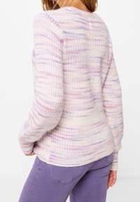 Sweter dzianinowy w jasnym odcieniu kremowym z fioletowymi i różowymi paskami, z okrągłym dekoltem i długimi rękawami, wykonany z fakturowanej, przytulnej tkaniny.