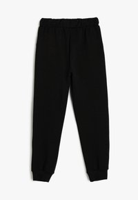 Schwarze, gerippte Jogginghosen mit einem elastischen Bund, schmal zulaufenden Beinen und enganliegendem Bündchen an den Knöcheln. Weiche Textur des gesamten Stoffes.
