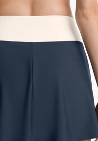 Námornícky športová sukňa s kontrastným svetlo krémovým pásom. Hladká, elastická tkanina s jemnou textúrou, s logom vzadu.