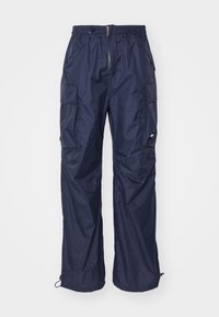 Pantalon cargo imperméable bleu marine avec ceinture élastique, poches latérales et cordons réglables au niveau des jambes.