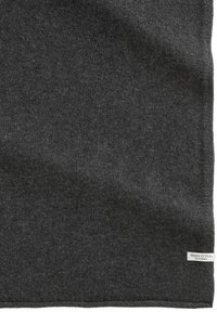 Donkergrijze gebreide stof met een klein wit rechthoekig merklabel van Marc O'Polo, dicht bij de onderrand genaaid.