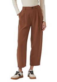 Brązowe spodnie o szerokich nogawkach z wysokim stanem, przednimi zakładkami i pojedynczym zapięciem na guzik. Stylizowane z casualowymi trampkami i lekkim topem.