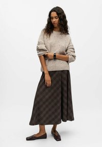 Pull en tricot beige, jupe longue à carreaux marron avec des lignes grises, et ballerines noires. Texture douce, coupe décontractée et longueur mi-mollet.