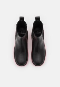 Paire de bottines noires en cuir à enfiler avec semelles roses, bouts arrondis et languettes de traction, vues de dessus sur un fond blanc.